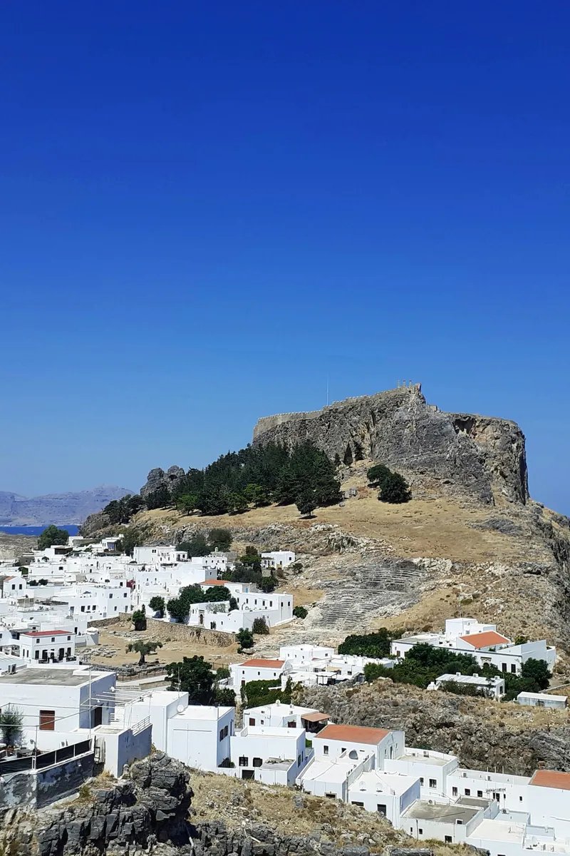 De zuilen van de Tempel van Athena Lindia op de Akropolis van Lindos, hoog boven het witgekalkte dorp en de blauwe Egeïsche Zee op Rhodos
